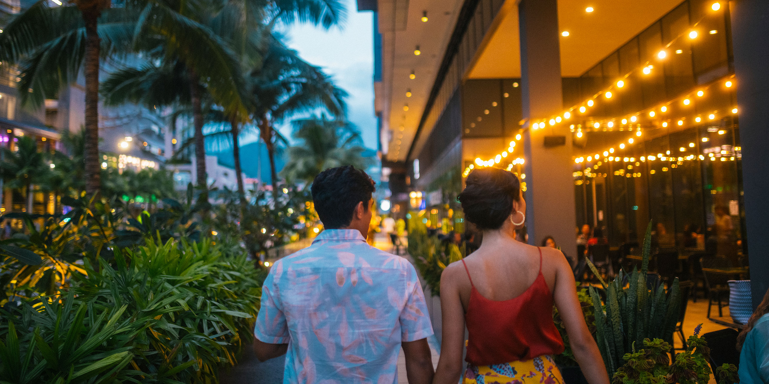 Couple walking through Ward Village at dusk.